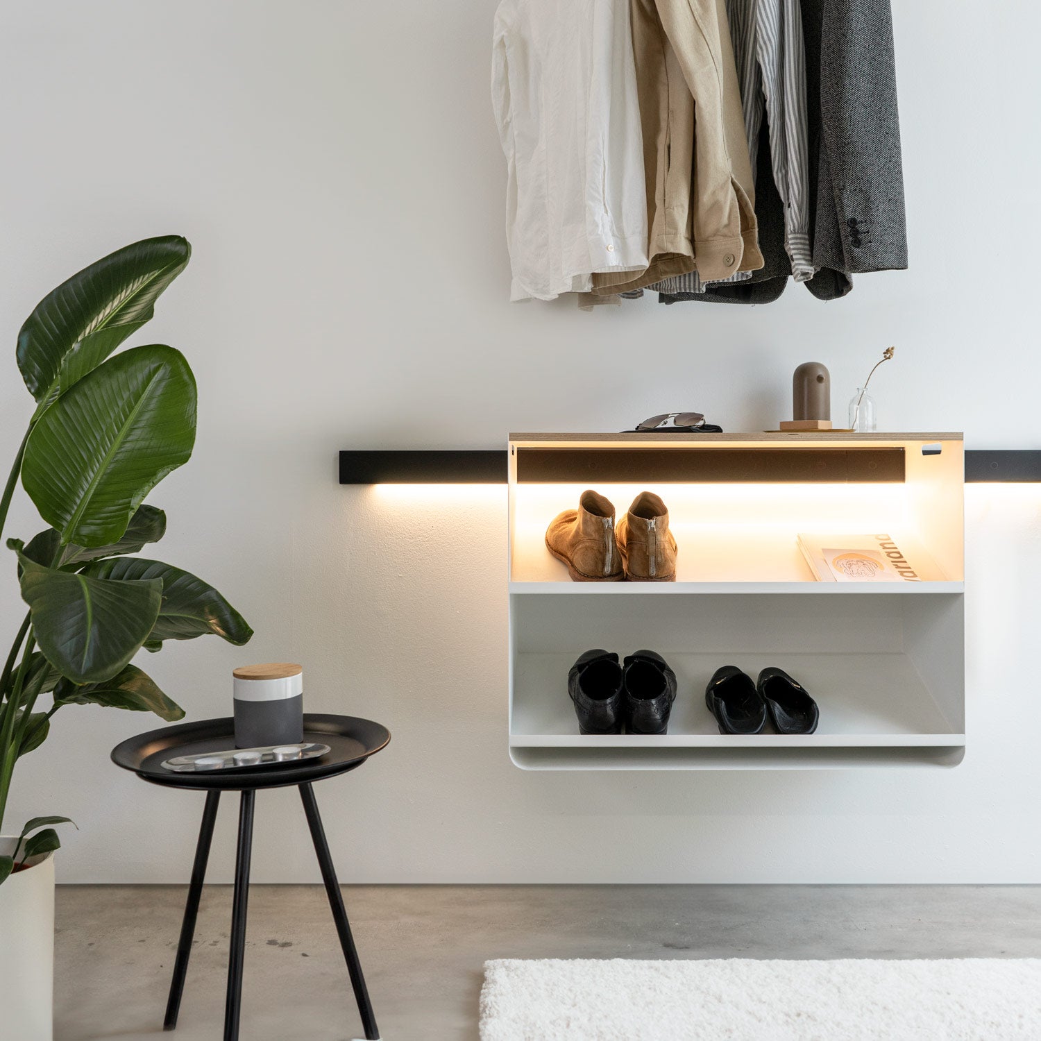 Wandgarderobe im Eingangsbereich mit dem minimalistischen Schuhregal von Variand an einer schwarzen Wandleiste aus Holz +hover